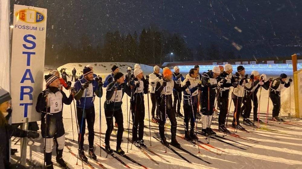 ca 20 deltagere med ski på beina venter på startskuddet på kvelden  snø på bakken og et skilt med start på begge sider 