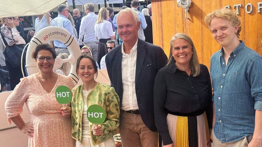 en gruppe glade foredragsholdere på storebrandbåten og to av dem holder små skilt med hot skrevet på