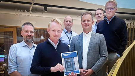 arbeidsgruppen står i trappa og personen foran holder veilederen